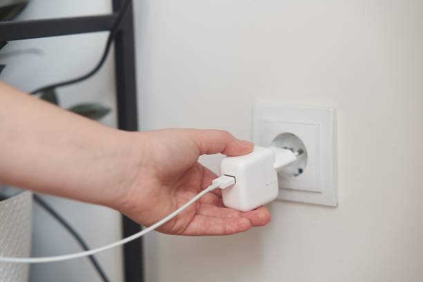 istock Young woman plugs the phone charger into the socket. 1498404537