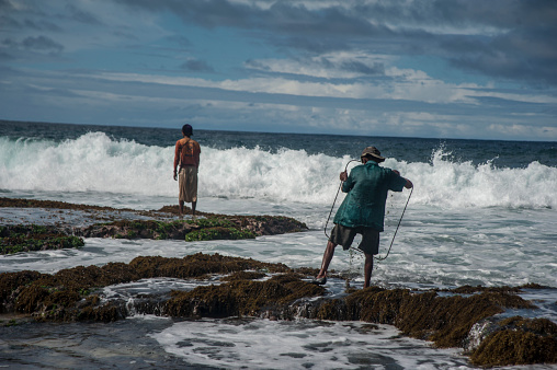 Gunungkidul, Yogyakarta, 5 August 2012 : Two fishermen looking for fish and lobsters at Timang Beach, Yogyakarta, Indonesia. After getting the fish and lobsters, they sell them to the traditional market.