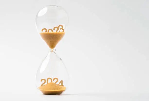 Photo of Sand inside of hourglass of change year from 2023 to 2024 for countdown of merry Christmas
and happy new year concept.