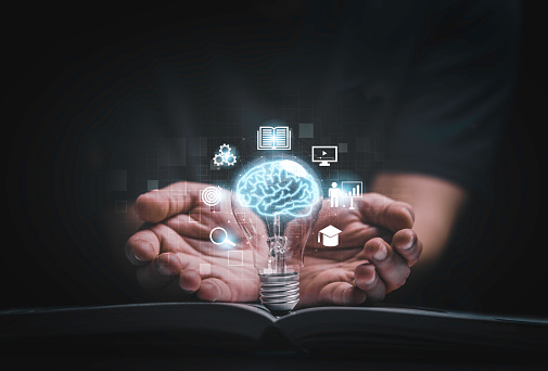 Virtual brain inside lightbulb on open book between two hand for creative thinking idea to solve problem from learning knowledge and innovation concept.