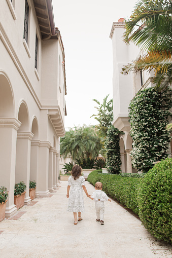 istock Lifestyle Candid Moment of a Brother & Sister Walking Together Holding Hands Wearing Sage Green & White Spring Wear in Palm Beach, Florida in May of 2023, Cuban-American 4-Year-Old Toddler Girl & 1-Year-Old Baby Boy Both with Light Brown Hair 1498410090