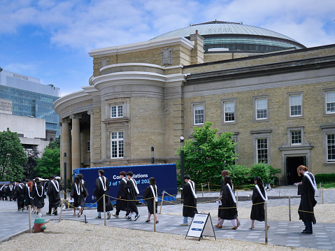 Canada - June 13, 2023: A procession of graduating university students in formal academic gowns go in to receive their diplomas