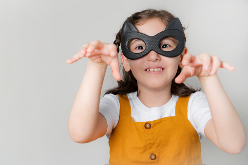 little girl wearing black cat mask isolated on white