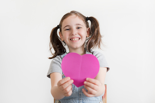 Cheerful kid holding pink heart-shape carton isolated on white