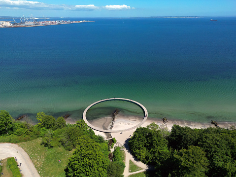 Panoramic aerial view of the seaside of Aahus and the round shaped Infinite Bridge in the foreground on a sunny day in Aarhus, Denmark