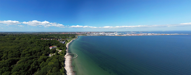 Panoramic aerial view of the seaside of Aahus and the round shaped Infinite Bridge in the foreground on a sunny day in Aarhus, Denmark