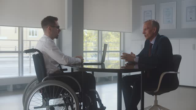 Disabled man at job interview in office talking to mature executive