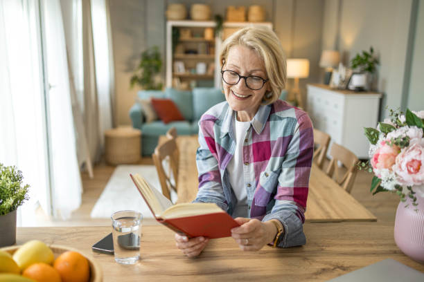 istock Retired senior woman enjoying spending time reading book 1498416069