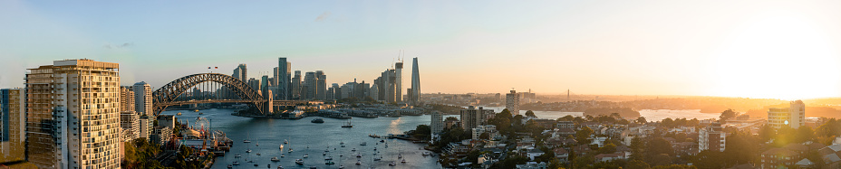 Panoramic cityscape looking over Sydney, Australia, during sunset. The view shows the Harbour Bridge and the Central Business District.