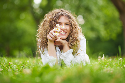 smiling beautiful young girl with curly hair in camomile field