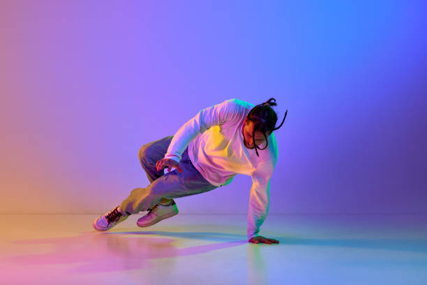 istock Young guy with dreads, in casual clothes dancing hip-hop, breakdance against gradient multicolored studio background in neon light 1498420706