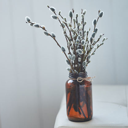 Easter decoration - a vase with willow branches on the table in a dark brown glass vase. Palm Sunday concept with copy space. High quality photo