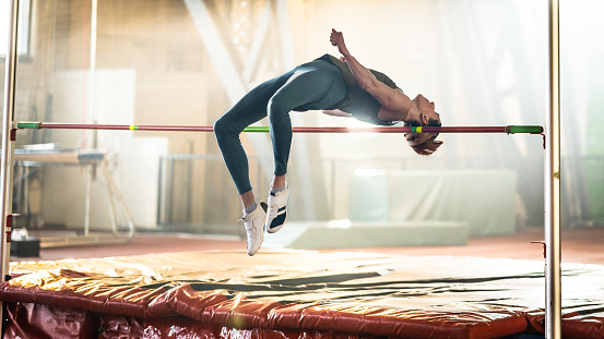 High jump, woman and fitness with exercise, sport and athlete in a competition outdoor. Jumping, workout and training for performance with action, energy and contest with female person and athletics
