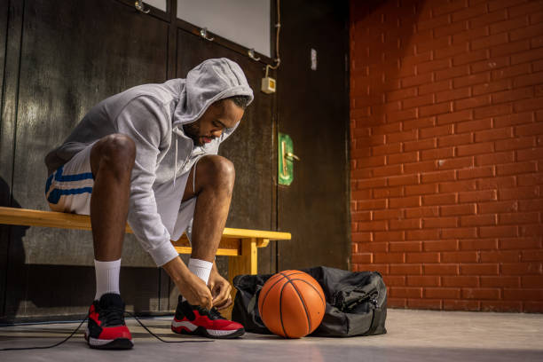 istock Basketball player tying  shoelace in locker room 1498429143