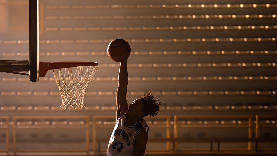 African american basketball player silhouette throwing ball through hoop while training medium shot side view