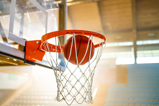 Basketball ball falling through net in outdoor court, scoring goal in team sport close up