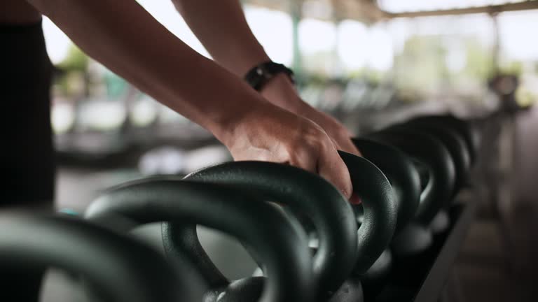 Woman takes dumbbell in gym.