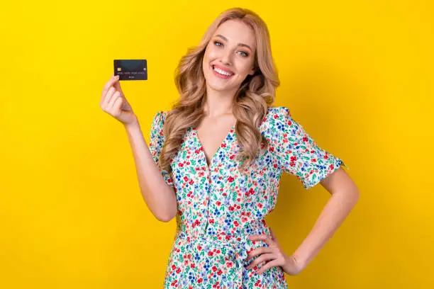 Photo of Portrait of pretty lovely positive lady wear trendy clothes demonstrate recommend use plastic card isolated on yellow color background
