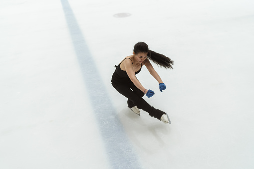 Asian female figure skater in black leotard practicing her skate routines