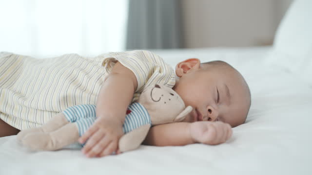 Portrait of a newborn boy sleeping and hugging his teddy bear. in the bed in the bedroom at home
