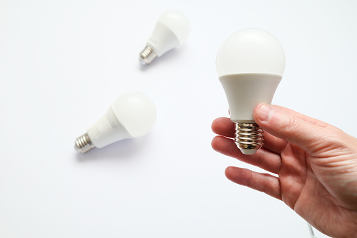 Man hand holding led light bulb on white background. Closeup. Energy saving. Point of view shoot. Power saving concept.