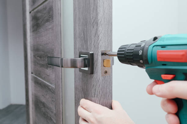 istock Handyman Fitting A New Door Using A Screwdriver At Home. Carpenter at lock installation with electric drill into interior wood door 1498435355