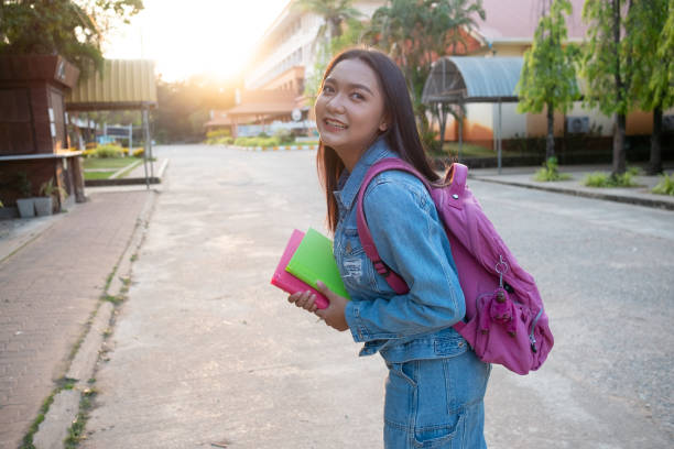 istock Happy young girl hold book with backpack walking at school. 1498435423