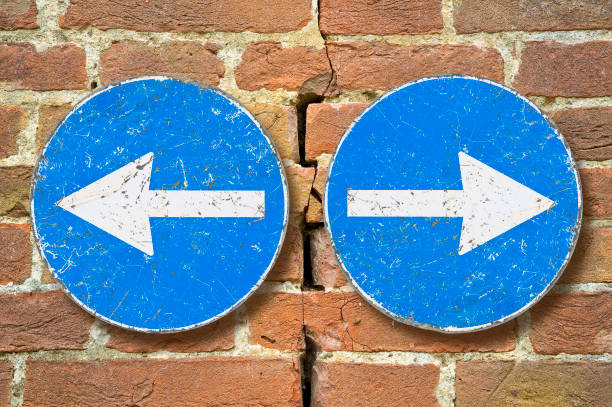 Old blue metallic arrow sign against an aged cracked brick wall indicating to go left and right - concept image stock photo
