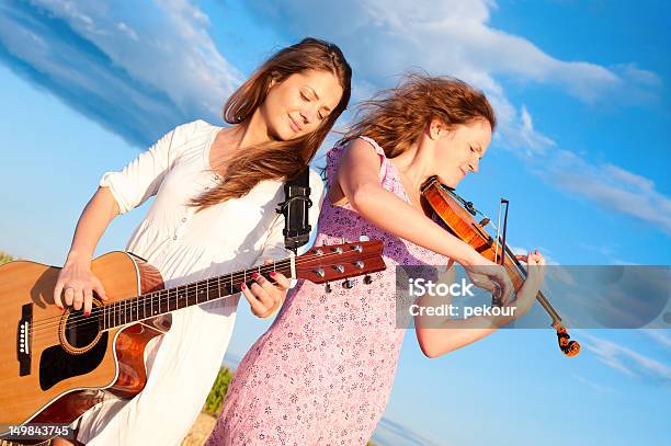 Photo libre de droit de Deux Jeunes Femmes Jouant De La Guitare Et Violon En Plein Air banque d'images et plus d'images libres de droit de Confiture