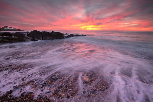 A vibrant and stunning sunset over an ocean wave with long exposure