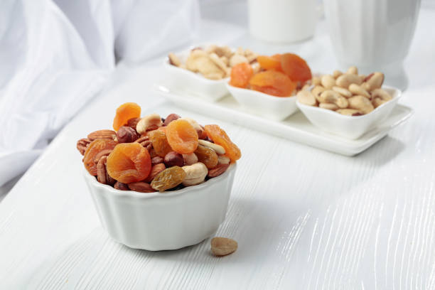 Dried fruits and assorted nuts on a white wooden table.