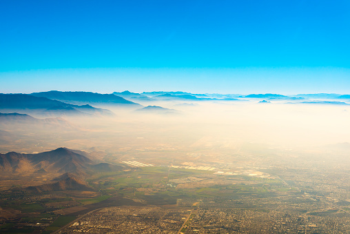 Aerial view of Santiago de Chile under a layer of smog trapped between the hills.
