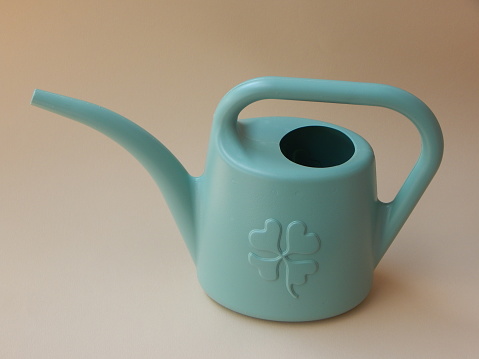 Watering can on beige background