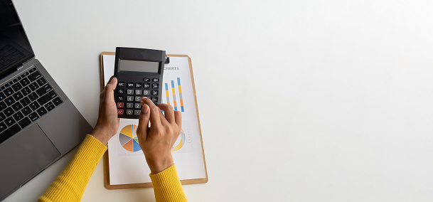 Close up view of businesswoman using calculator to estimate the budget for company.