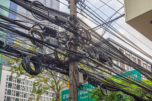 Bangkok, Thailand - March 27th 2023: Typical Asian cable work with a confusing mesh of cables in the center of the capital of Thailand