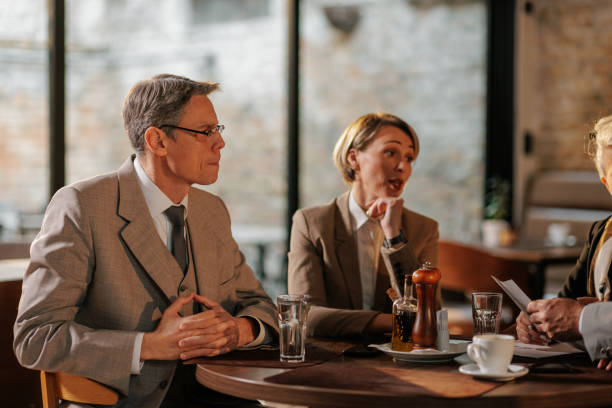 A group of Caucasian businesspeople are gathered in an informal meeting in a cafe.