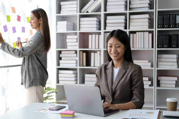 istock Young busineswoman with team brainstorming by use post it notes to share idea on glass wall. 1498452248