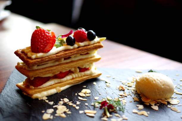 Strawberry and cream napoleon stack cake biscuit shortbread with ice cream ball on black slate plate
