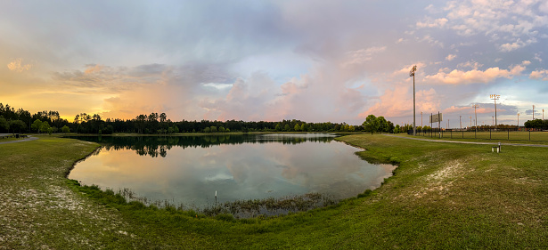 A colorful sky is reflected in a lake alongside a walking trail and softball field in Waycross, Georgia.