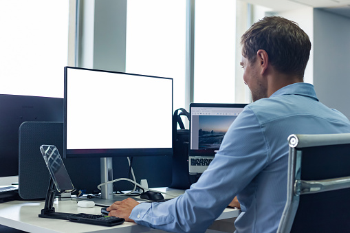 Cropped image of a professional caucasian businessman sipping coffee and working on his business tasks on laptop at his desk.