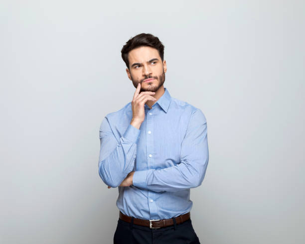 istock Thoughful businessman standing with hand on chin 1498457141