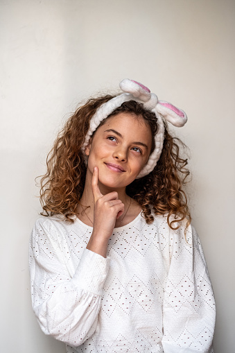 Close up of a smiling girl holding a painted easter egg in front of her face. Girl wearing rabbit ear headband having fun playing with painted eater egg.