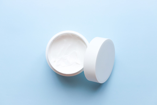 Flat lay face cream on blue background. Spa, beauty. Personal care.