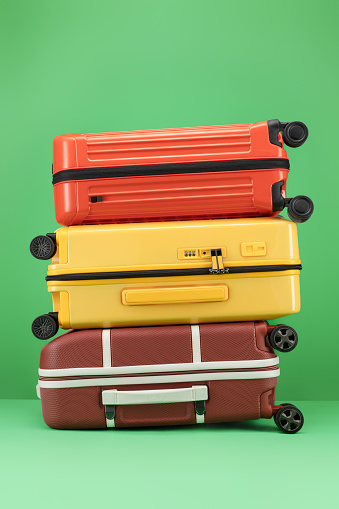 Travel Yellow, orange color, brown suitcase on a green background. Travel and vacation concept in triples. Stylish suitcases on color background. Trolley suitcase.