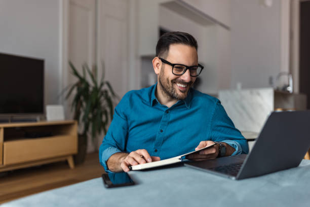 istock Smiling businessman having an online meeting with colleagues, writing notes in a notebook. 1498462847