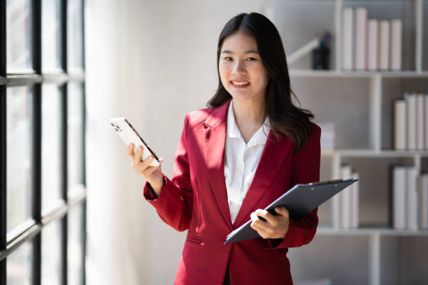 istock Charming Asian businesswoman using her mobile phone while working in the glass modern office room in the company. 1498463847