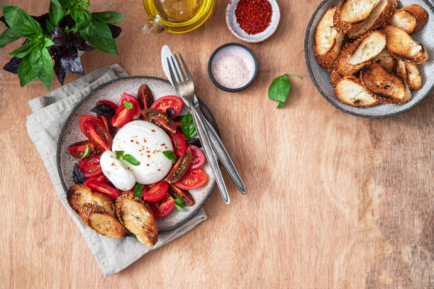 istock Salad with Burrata cheese, tomatoes and basil on wooden background. 1498464251