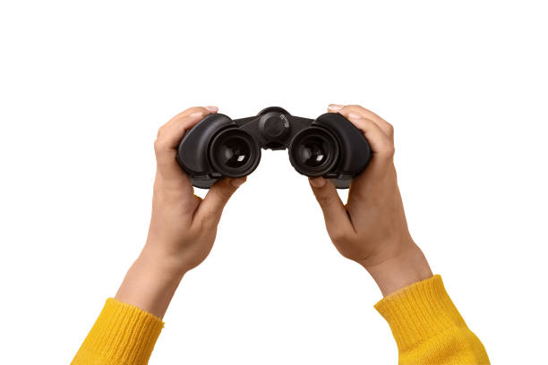 istock binoculars in hand isolated on white background, find and search concept. 1498465647