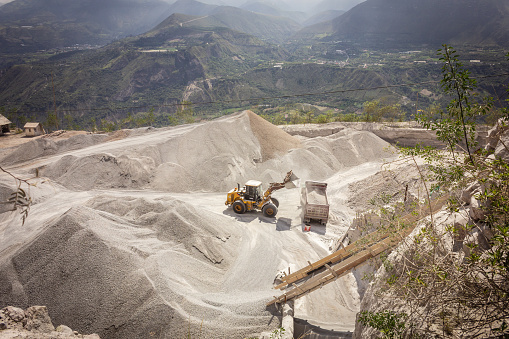 loader placing stone material into a dump truck for transportation