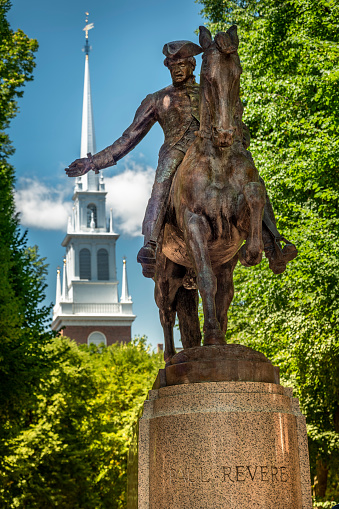 Boston, USA - July 19, 2022:  Paul Revere statue on the historic Boston Freedom Trail with the Old North Church steeple in behind in Boston Massachusetts USA